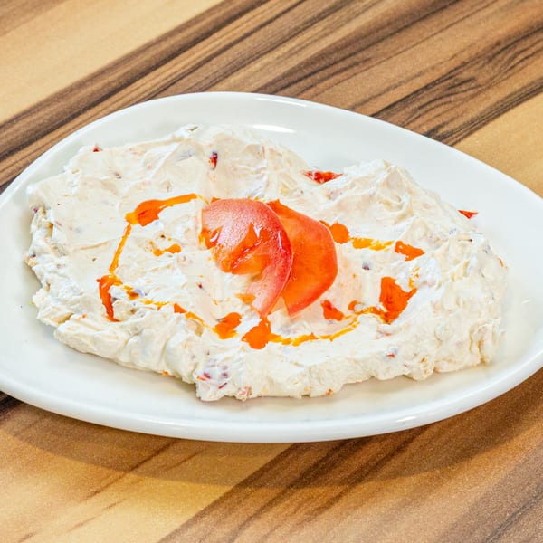 Turkish Haydari dip, a creamy yogurt and herb spread, garnished with tomato slices and chili oil.